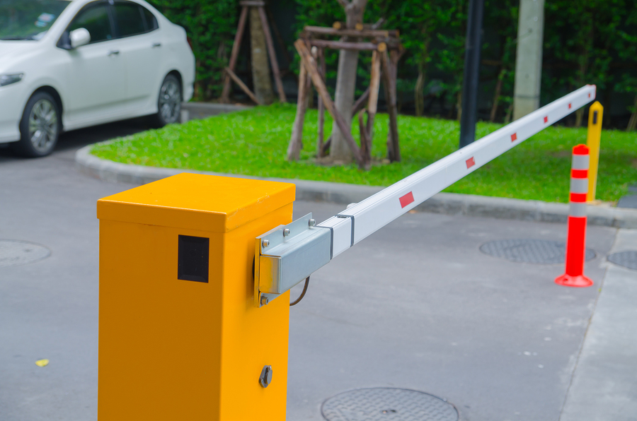 Automatic driveway access gate with yellow post and white arm, offering security and controlled entry to a property.